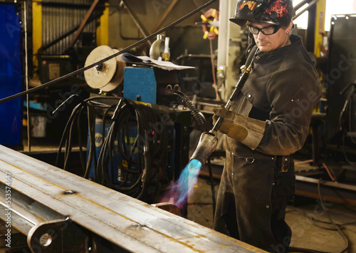Tradesman pre-heating steel beam with a lift lug using a torch; Innisfail, Alberta, Canada