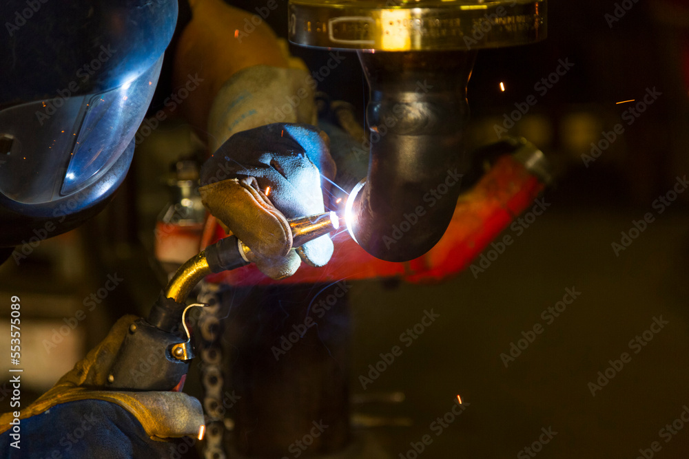 A pipe fitter tack welding piping for a flange fitting in a metal