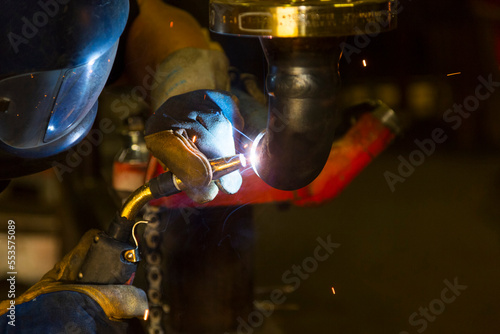 A pipe fitter tack welding piping for a flange fitting in a metal fabrication plant; Innisfail, Alberta, Canada photo