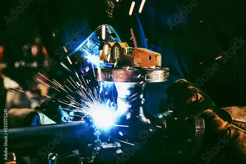 A journeyman welder attaching flanges to a pipe uses tack welding for pipe fitting alignment in a metal fabrication plant; Innisfail, Alberta, Canada photo
