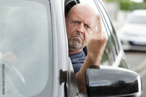 mature man driving in his car swearing and looking angry photo