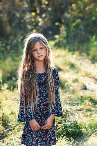 A portrait of a pretty little girl with long hair in a city park during the fall season; Edmonton, Alberta, Canada photo