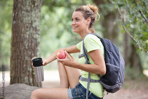Fototapeta Naklejka Na Ścianę i Meble -  woman hiker sitting relaxing after hiking eating apple