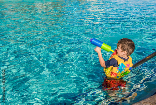 A young boy plays in a swimming pool with a watergun at a resort in Ka'anapali; Ka'anapali, Maui, Hawaii, United States of America