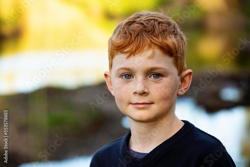 Outdoor portrait of boy with red hair and freckles and blurred autumn colours in the background; Edmonton, Alberta, Canada photo