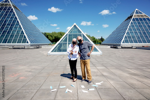 A mature couple stands outside wearing their face masks with masks littering the ground in front of them, during the Covid-19 pandemic; Edmonton, Alberta, Canada photo