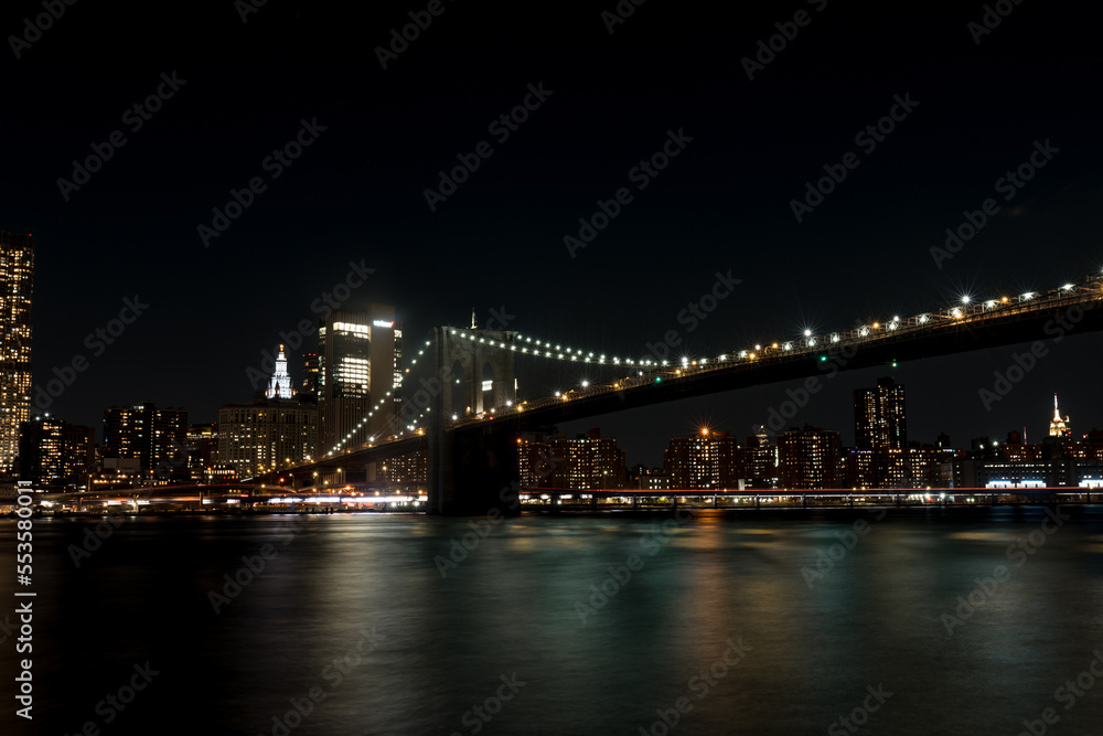 Brooklyn Bridge in New York at night. Skyscrapers of a large metropolis. Night city at long exposure. Towers in the big city.