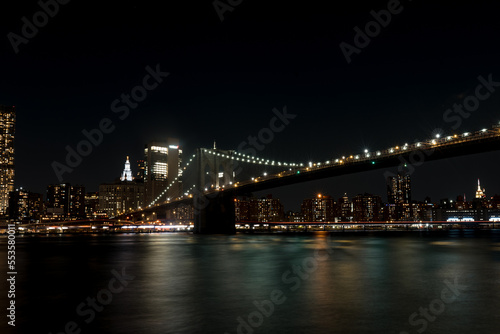 Brooklyn Bridge in New York at night. Skyscrapers of a large metropolis. Night city at long exposure. Towers in the big city.