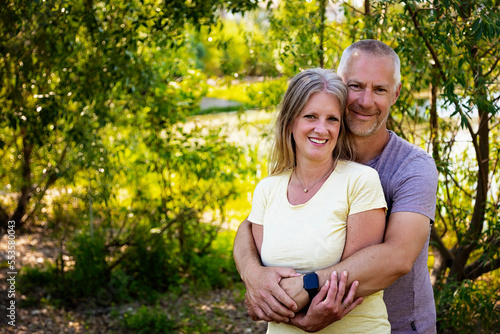 Outdoor portrait of a mature married couple standing posed in a park; Edmonton, Alberta, Canada