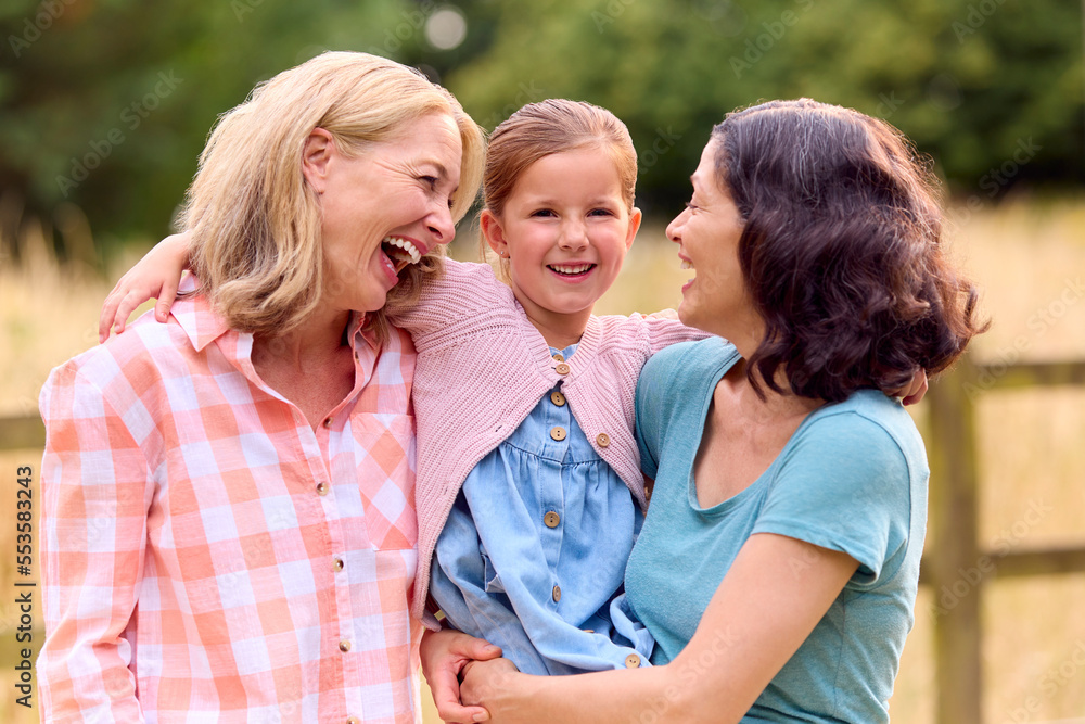 Portrait Of Same Sex Family With Two Loving Mature Mums Hugging Daughter On Walk In Countryside Portrait Of Same Sex Family With Two Loving Mature Mums Hugging Daughter On Walk In Countryside