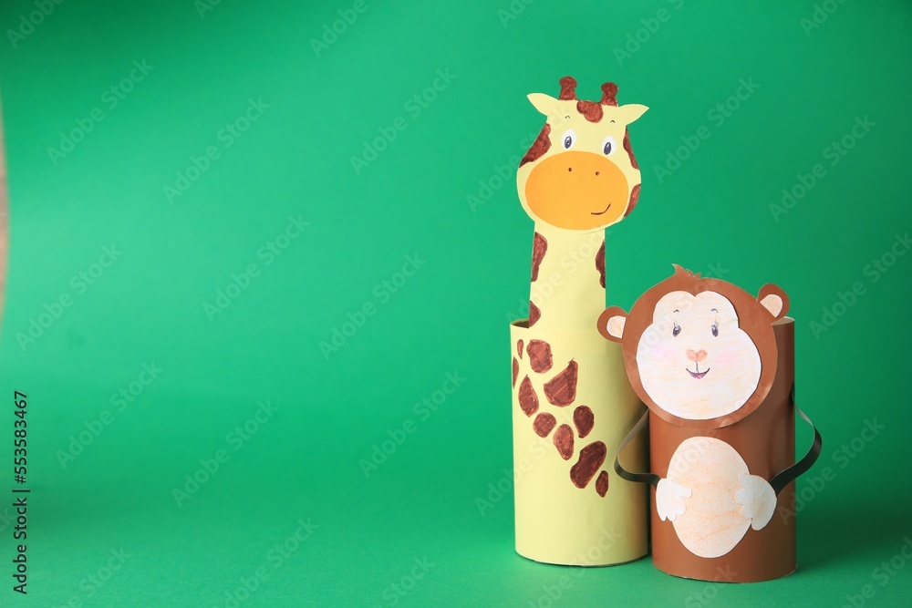 Fototapeta premium Toy monkey and giraffe made from toilet paper hubs on green background, space for text. Children's handmade ideas
