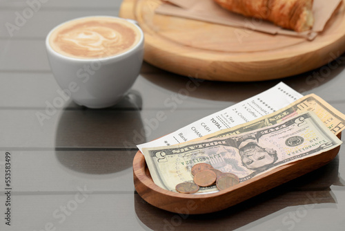 Tips, receipt and cup with coffee on wooden table photo