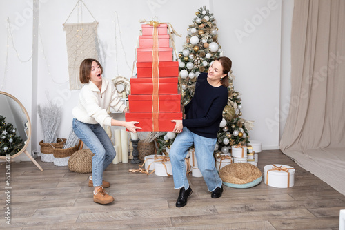 Young woman and her senior mother carrying a big amount of gift boxes and celebrating Christmas together at home © Vitaliy