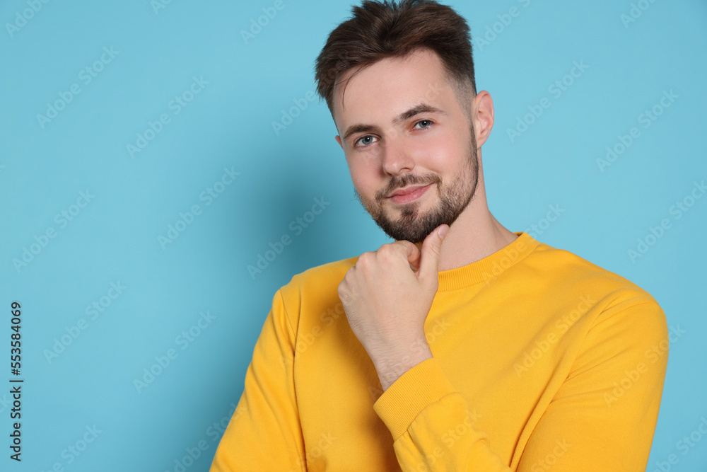 Handsome man in yellow sweatshirt on light blue background, space for text Handsome man in yellow sweatshirt on light blue background, space for text