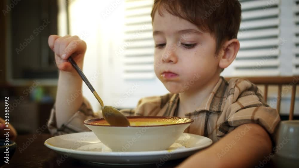 Close up pretty little boy with sitting at dining table in domestic kitchen eating dry breakfast potatoes soup. Balanced meal for child healthy growth concept.Child eating healthy organic vegan food. Close up pretty little boy with sitting at dining table in domestic kitchen eating dry breakfast potatoes soup. Balanced meal for child healthy growth concept.Child eating healthy organic vegan food.
