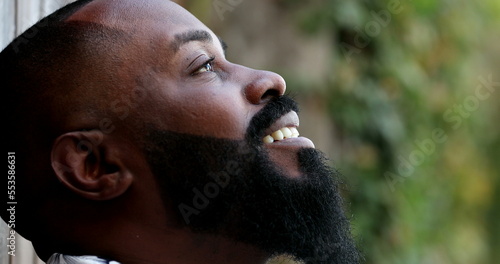 Happy optimistic black African man smiling looking at sky with HOPE and FAITH