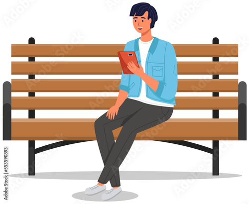 Young man sitting on bench calling on video with tablet. Online communication, interaction with phone, taking pictures, reading, chatting. Smiling male character recording podcast on his smartphone