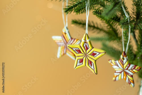 Ceramic Christmas stars on fir branches on beige background © Syoma Barva