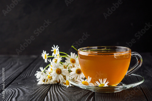 aromatic hot chamomile tea on a black rustic wooden background