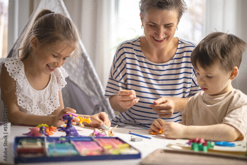 Caring mother sculpt dinosaurs from plasticine early development with boy and girl kids Caring mother sculpt dinosaurs from plasticine early development with boy and girl kids