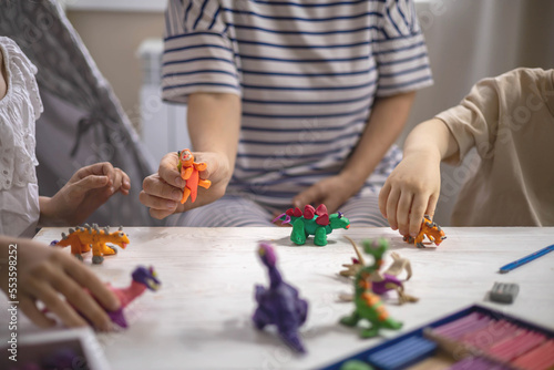 Caring mother sculpt dinosaurs from plasticine early development with boy and girl kids