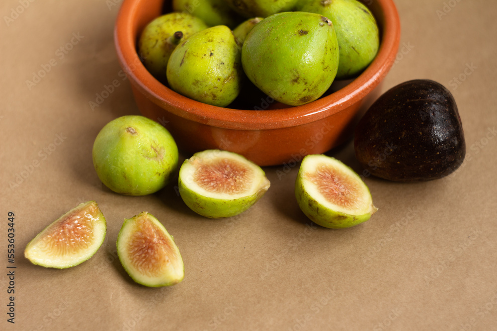 close-up of figs cut in half and figs in clay bowl on light brown background
