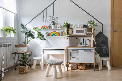 White childish kitchen interior early development playroom with Montessori wooden materials