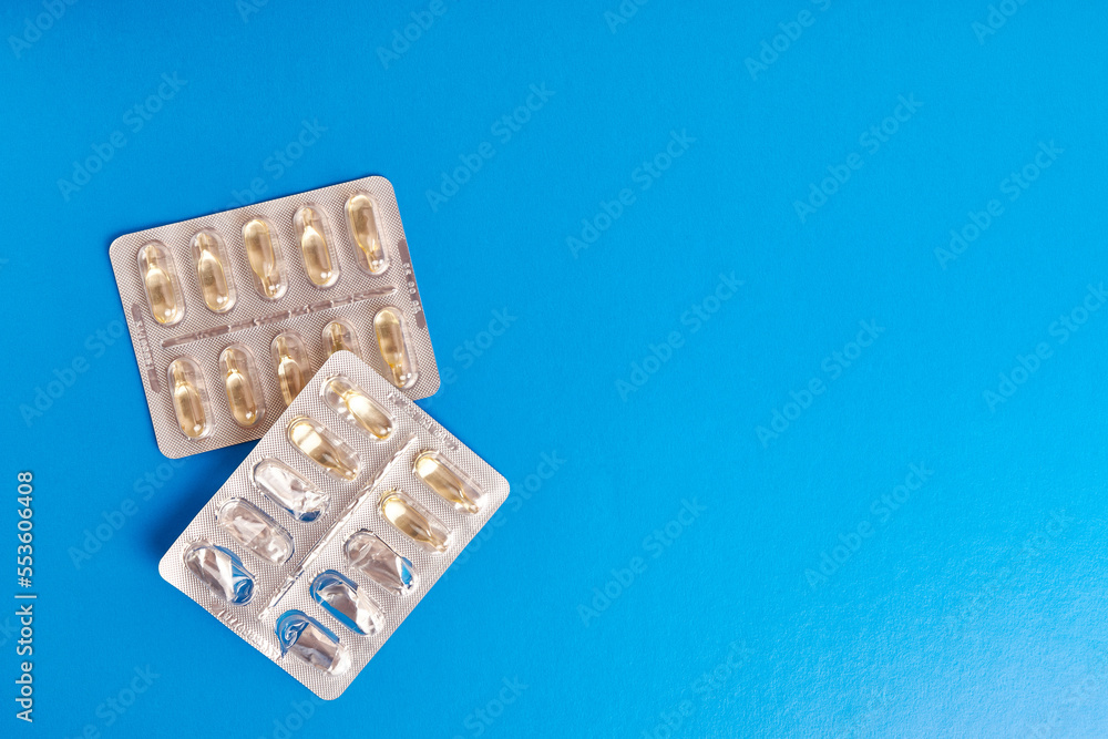 Vitamins in the form of capsules on a blue background. Treatment and prevention of diseases. Strengthening immunity. Vitamins in the form of capsules on a blue background. Treatment and prevention of diseases. Strengthening immunity.