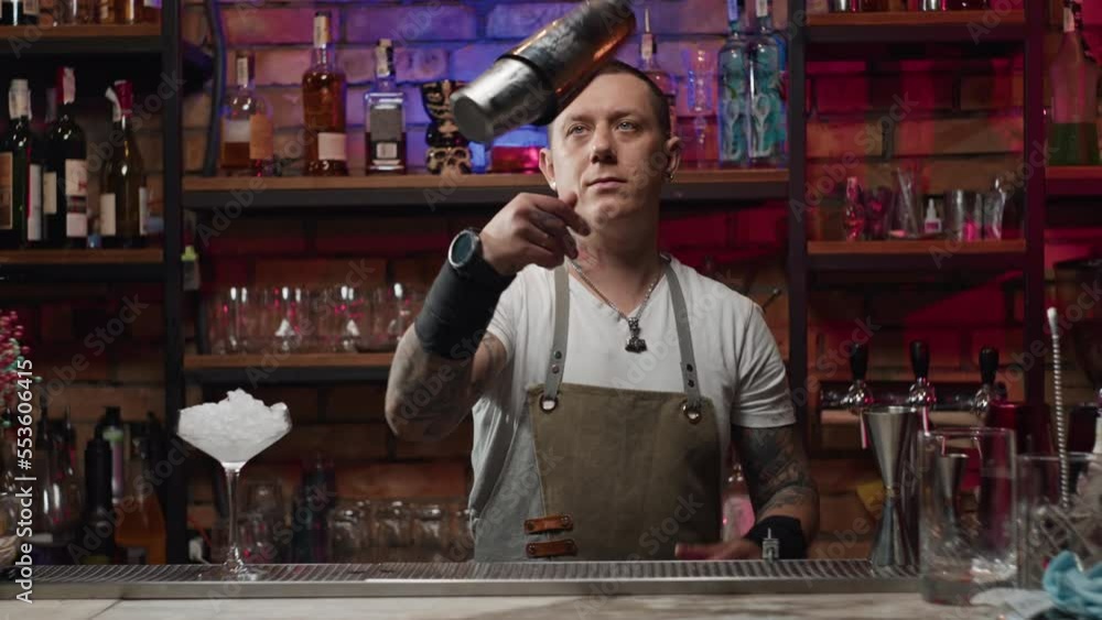 Slow motion video of a bartender shaking a cocktail at the bar with a