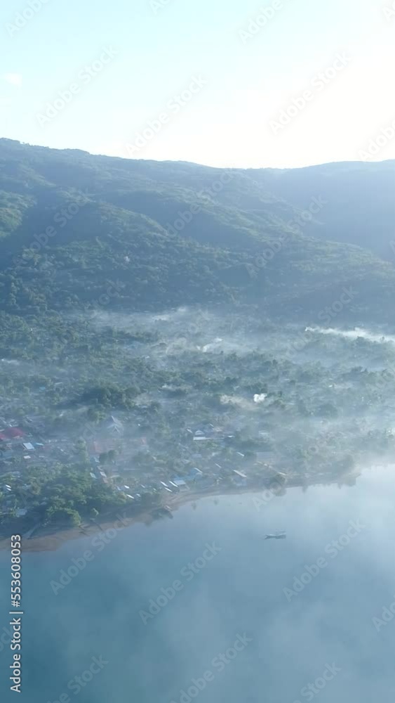 Vertical video of Aerial shot of a city of a tropical island under the morning fog Vertical video of Aerial shot of a city of a tropical island under the morning fog