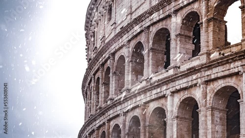Rome christmas lights blurred while snow falling in slow motion. Grey clouds in background. Coliseum or Flavian Amphitheatre (Amphitheatrum Flavium or Colosseo), Rome, Italy.