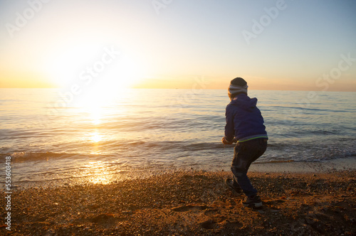 A little boy is standing on the beach near the sea © Andrii Salivon