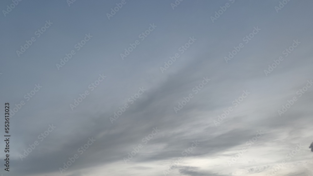 Light gray sky with clouds. Winter evening. High cirrus clouds of various shapes and sizes. The clouds are white in places translucent, through which a gray blue sky is visible. Light gray sky with clouds. Winter evening. High cirrus clouds of various shapes and sizes. The clouds are white in places translucent, through which a gray blue sky is visible.