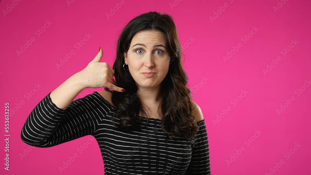 Portrait of smiling happy young woman 20s smiling and giving call me gesture with hands isolated on pink background. Portrait of smiling happy young woman 20s smiling and giving call me gesture with hands isolated on pink background.