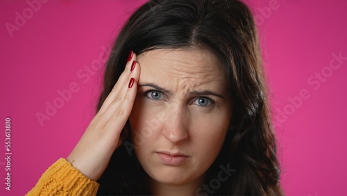 Closeup portrait of sick tired headache migraine exhausted displeased pretty woman 20s posing isolated on pink background studio. Put hands on head rub temples