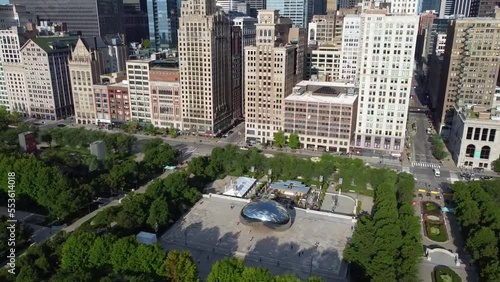 Aerial pan over Chicago Millennium Park aerial view of iconic Cloud Gate Bean by skyscrapers