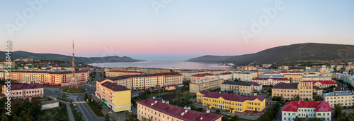 Wide panorama of the city of Magadan. Beautiful morning cityscape at dawn. Aerial view of streets, buildings and TV tower. In the distance is Nagaev bay and mountains. Magadan region, Russian Far East