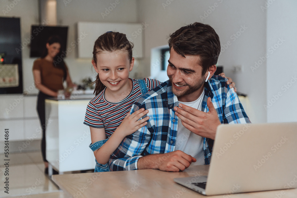 Father and daughter in modern house talking together on laptop with their family during holidays. The life of a modern family Father and daughter in modern house talking together on laptop with their family during holidays. The life of a modern family