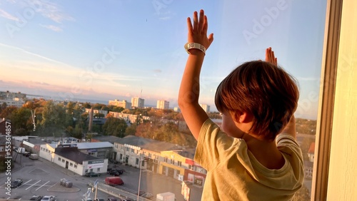 Pre-school boy looking out of the window of a skyscraper