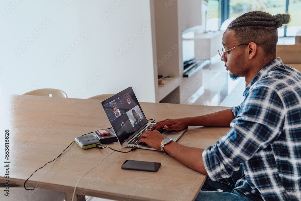 © .shock - African American man in glasses sitting at a table in a modern living room, using a laptop for business video chat, conversation with friends and entertainment © .shock - African American man in glasses sitting at a table in a modern living room, using a laptop for business video chat, conversation with friends and entertainment