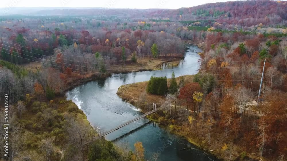 Aerial right over Michigan river with suspension bridge and fall colors Aerial right over Michigan river with suspension bridge and fall colors