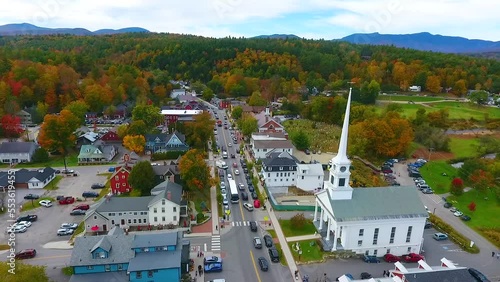 Aerial through beautiful small Vermont town of Stowe in peak fall foliage with focus on church photo