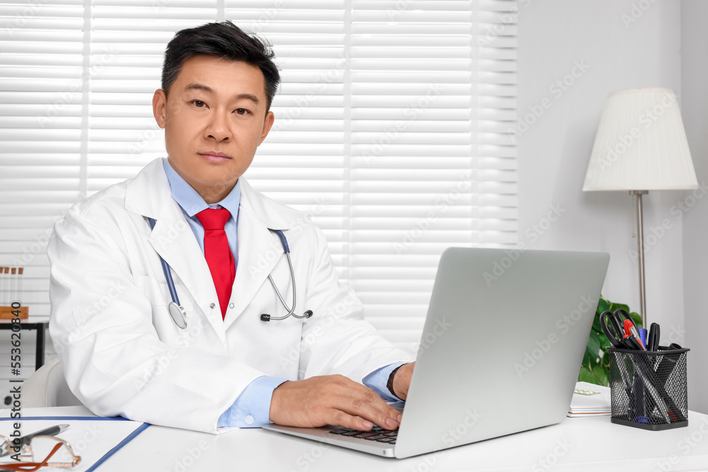 Doctor with laptop consulting patient at white desk in clinic. Online medicine Doctor with laptop consulting patient at white desk in clinic. Online medicine