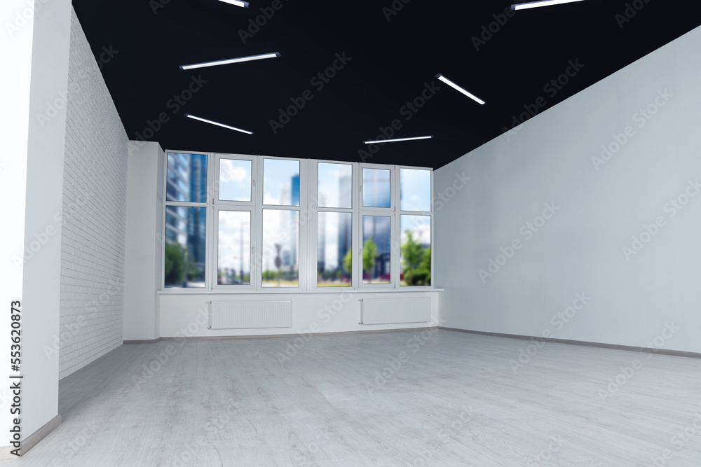 Fototapeta premium Empty office room with black ceiling and clean windows. Interior design