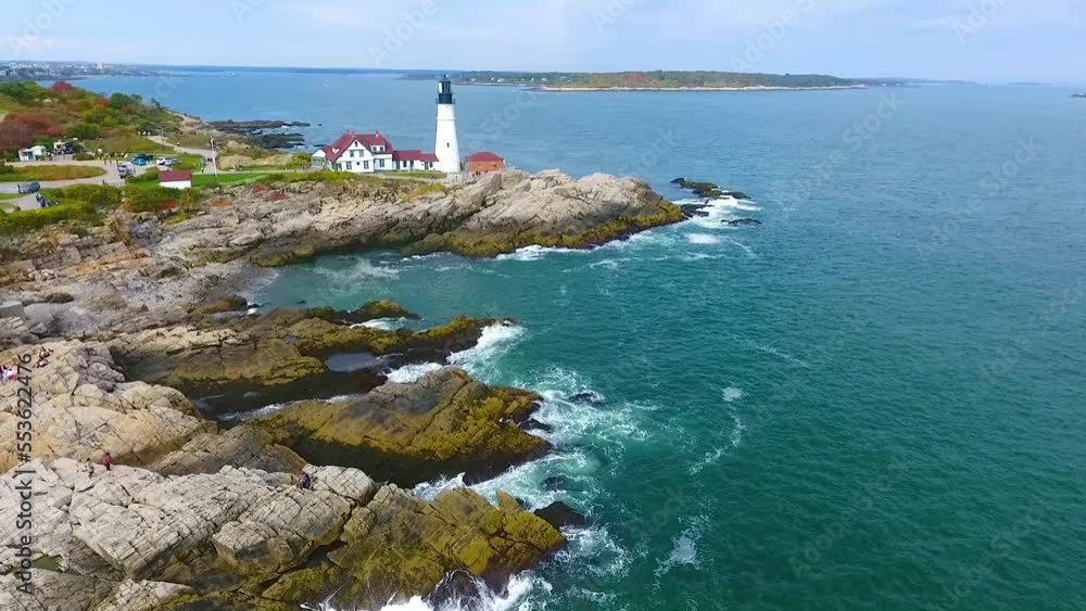Aerial over stunning rocky coastlines of Maine with crashing waves and white lighthouse Aerial over stunning rocky coastlines of Maine with crashing waves and white lighthouse
