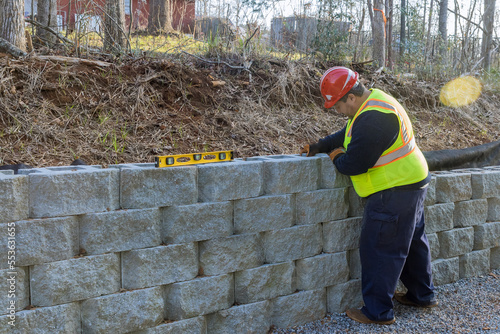 Man leveling tool building retaining concrete block wall with being built on new property photo