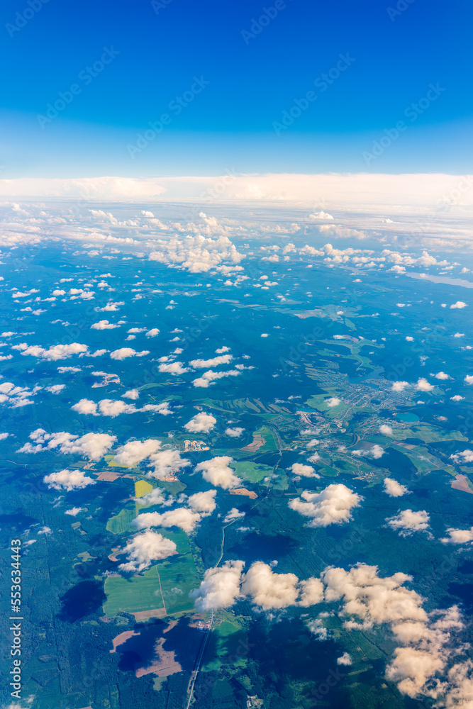 Aerial view from airplane window above green ground. View from the airplane window with beautiful clouds at sunrise