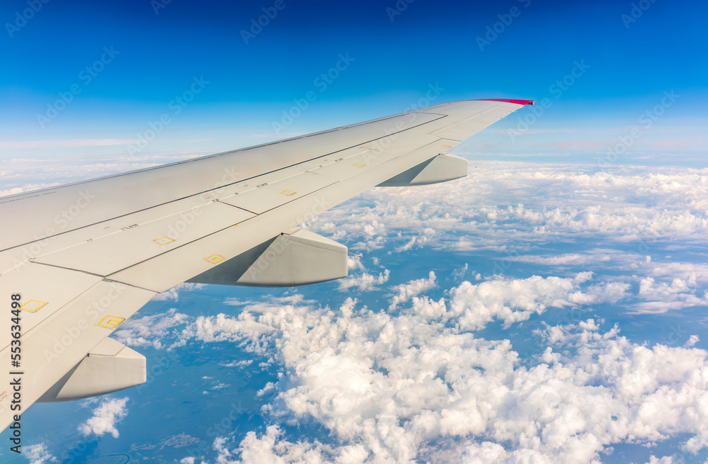 View from the airplane window at a beautiful cloudy sky and the airplane wing View from the airplane window at a beautiful cloudy sky and the airplane wing