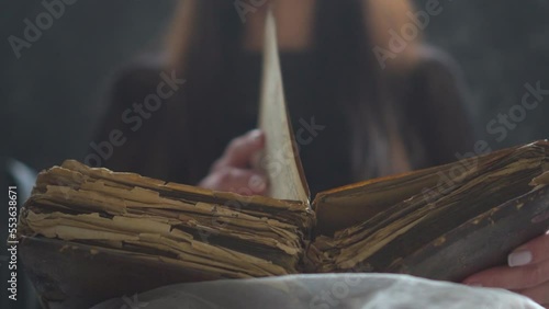 an old book in the hands of a woman. book with old pages. magical history book. old book, manuscript