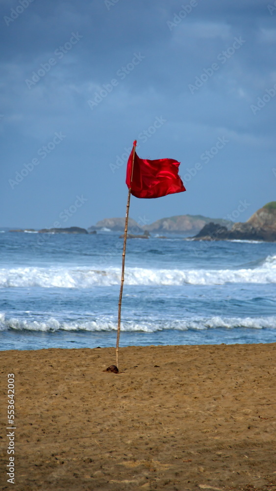 Red warning flag on the beach at sunrise, in Zipolite, Mexico Red warning flag on the beach at sunrise, in Zipolite, Mexico